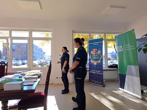 dwie policjantki, za nimi banery z napisem policja, zus.