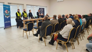 policjanci, przed nimi osoby siedzą na krzesłach, w tle napis policja, dzielnicowy bliżej nas.