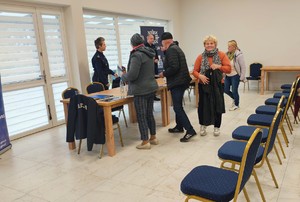 kilka osób przed stołem, za stołem policjanci.