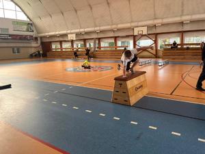chłopiec przeskakuje przez skrzynię na sali gimnastycznej.