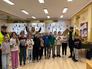 policjantki z dziećmi i kobietą pokazują zawieszki odblaskowe.