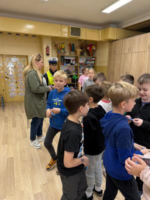 dzieci, za nimi kobieta i policjantka.