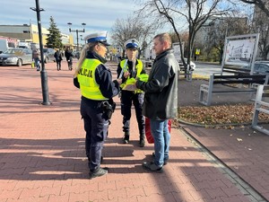 mężczyzna z policjantkami, chodnik, budynki.