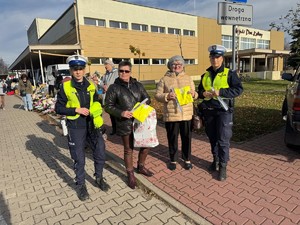 dwie policjantki i dwie kobiety trzymają kamizelki odblaskowe.