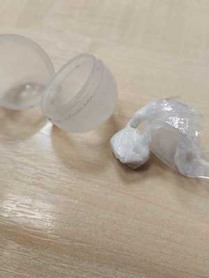 pudełko plastikowe, biały proszek w torebce foliowej.