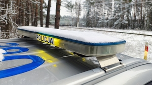 dach radiowozu policyjnego, napis policja, w tle tory, śnieg.