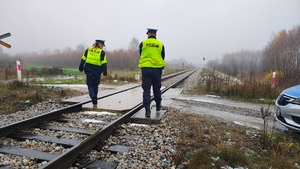 policjanci w kamizelkach odblaskowych znajdują się na przejeździe kolejowym.
