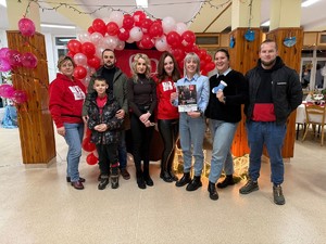 kobiety i mężczyźni stoją przy choince i paczkach, prezentach.