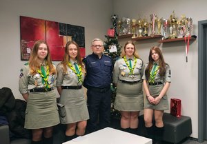 policjant z harcerkami, za nimi choinka.