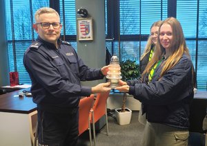 policjant z harcerkami, trzymają znicz.