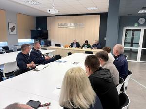 grupa ludzi znajduje się w sali konferencyjnej komendy policji.