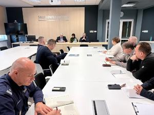 policjanci i osoby bez mundurów siedzą przy stołach sali konferencyjnej policji.