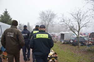 mężczyźni w kurtkach z napisami straż leśna, straż miejska, policja, targowisko.