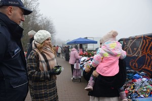kobieta w białej czapce rozmawia z kobietą trzymająca dziecko na rękach, targowisko.