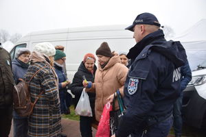 policjant, kobieta w białej czapce, ludzie pomiędzy straganami.