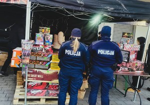 policjantki w mundurach stoją przy stoisku z fajerwerkami.