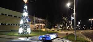 dach radiowozu, oświetlona choinka, budynek i ulice.