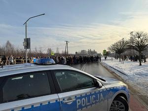 grupa ludzi idzie ulicą, radiowóz policyjny.