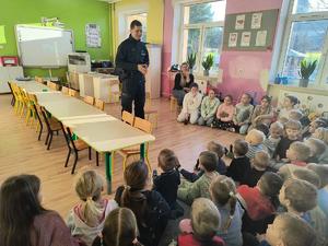policjant stoi między ławkami w klasie.