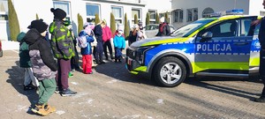 dzieci i policjantka stoją przy policyjnym radiowozie.
