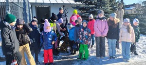 dzieci wraz z policjantem bez munduru, pies znajdują się przy kojcu.