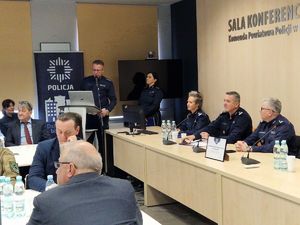 policjanci i grupa ludzi siedzą za stołami, policjant stoi przy mównicy na sali konferencyjnej komendy policji w Opocznie.