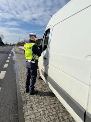 policjant w odblaskowej kamizelce stoi przy busie.