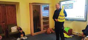 policjant trzyma w ręku kamizelkę odblaskową.