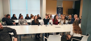 grupa ludzi, policjanci siedzą za stołami.