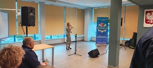 dziewczyna w kolorowej sukience z mikrofonem, na sali komendy policji.