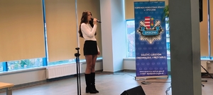 młoda kobieta w krótkiej spódniczce z mikrofonem na sali komendny policji.