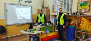 dwóch policjantów w odblaskowych kamizelkach w klasie szkolnej.