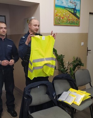 policjanci w mundurach, jeden trzyma odblaskową kamizelkę.