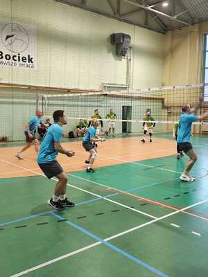 widok na osoby grające w piłkę siatkową na sali gimnastycznej.