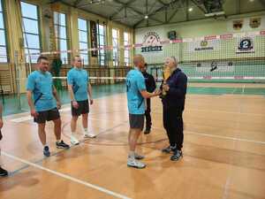 policjant wręcza puchar zawodnikowi, inni zawodnicy stoją za nim.