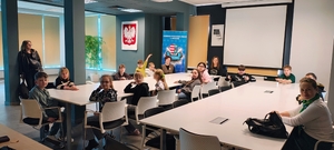 dzieci , trzy kobiety siedzą na sali , w tle napis komenda powiatowa policji w Opocznie.