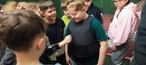 dzieci znajdują się na strzelnicy, jedno dziecko w kamizelce koloru czarnego.