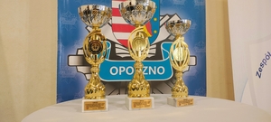 trzy puchary, w tle logo policji opoczyńskiej.