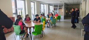 przy stolikach siedzą dzieci, przed nimi policjantka.