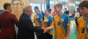 mężczyźni podają rękę dzieciom w sportowych strojach.