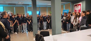 policjantka stoi przed młodzieżą, w pomieszczeniu komendy, napis komenda powiatowa policji w Opocznie.