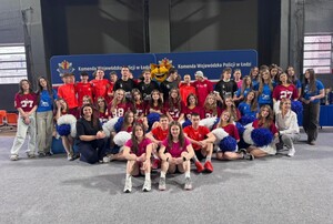 grupa młodzieży, część z pomponami, wszyscy ubrani na sportowo.