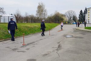 policjant stoi przy torze przeszkód, po którym jedzie dziecko na rowerze.