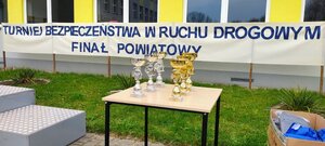 napis na budynku turniej bezpieczeństwa w ruchu drogowym finał powiatowy, na stoliku stoją puchary.