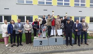 dzieci z pucharami stoją na podium, obok policjanci, kobiety i mężczyźni.
