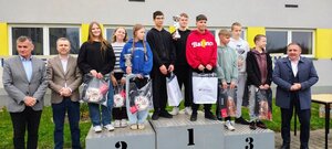 dzieci z pucharami stoją na podium, obok policjanci, mężczyźni i kobiety.