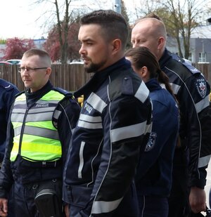 kilku policjantów w mundurach, jeden w kamizelce odblaskowej stoją na placu, na ziemi stoją pachołki.