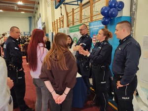 policjanci rozmawiają z młodzież przy stoisku policyjnym na targach pracy.