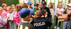 dzieci z policjantem znajdują się w pomieszczeniu strzelnicy.