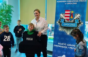 chłopiec ubrany w kamizelkę z napisem policja, przy nim kobieta.